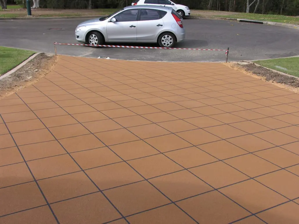 Tan decorative concrete resurfacing with charcoal grout lines in a diamond tile pattern across a suburban Brisbane driveway