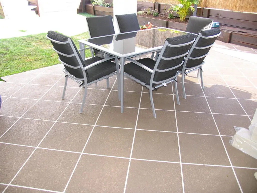Brown speckled concrete patio resurfaced in a square tile grid with white grout, outdoor setting on top