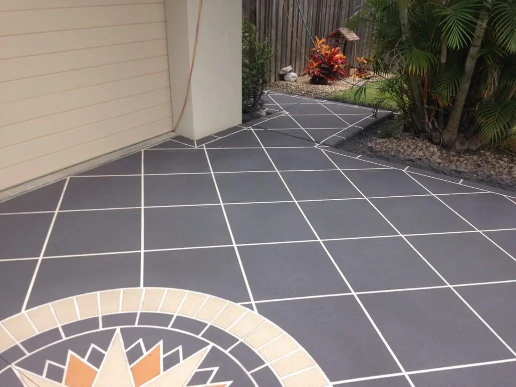 Charcoal spray-on concrete driveway with crisp white grout lines and a custom sunburst star motif set into the surface
